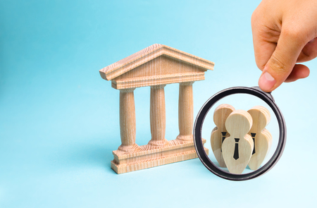 116140720-magnifying-glass-is-looking-at-the-figures-of-people-in-ties-stand-near-the-government-building-or-t